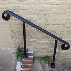 an iron hand rail next to a brick wall