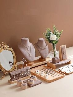 an assortment of jewelry sits on a table next to a vase with flowers in it