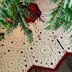 there is a crocheted blanket on the floor next to a christmas tree branch