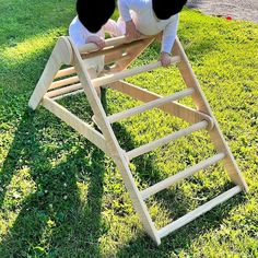 two babies playing on a wooden sled in the grass