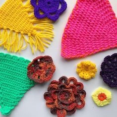 crocheted hats and flowers are laid out on a white surface, ready to be knitted