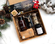 an open gift box with candles, jams and other holiday treats on it next to some cotton balls