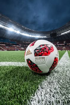 a soccer ball sitting on top of a green field in front of an empty stadium