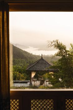 a gazebo sitting in the middle of a lush green forest next to a lake