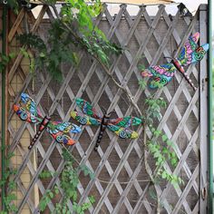 three colorful dragon sculptures sitting on top of a wooden fence next to a tree branch