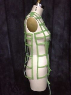 a white and green vase with a bottle in the shape of a cage on it