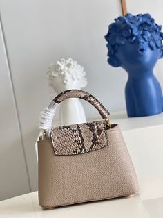 a handbag sitting on top of a table next to a vase with flowers in it