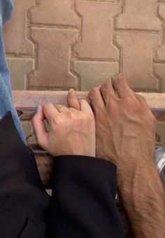 two people are sitting on a bench with their hands touching each other's fingers