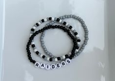 These Raiders bracelets are the perfect way to show your team pride for the big game! Pair them with any outfit. This listing is for 3 bracelets as shown in pictures.  TO ORDER:  1. Pick bracelet length  2. Pick letter color 3. Submit and I'll get to work :)  PRODUCT DETAILS:  - Bracelets are made with sturdy jewelry elastic - Listing is for three bracelets  - All orders are final. Please double check your bracelet size  CARING TIPS:  - Do not expose jewelry to water  - Treat and store jewelry gently  - Roll bracelets on rather than stretching band to get on Don't see your teams bracelets on our shop? Or have a custom team bracelet you want? Head to this link to order your custom ones!  https://kanaeohana.etsy.com/listing/1591607617/custom-sports-team-bracelets-team   We are HAPPY to do bu Personalized Black Sporty Bracelets, Team Spirit Bracelets With Letter Beads, Sporty Beaded Bracelets In Team Colors For Sports Events, Sporty Personalized Black Bracelets, Casual Beaded Bracelets In Team Colors For Sports Events, Sporty Personalized Black Bracelet, Sporty Team-colored Beaded Bracelets For Sports Events, Casual Team-colored Beaded Bracelets For Sports Events, Casual White Bracelets For Team Events