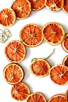 orange slices arranged in the shape of a circle on a white surface with green stems