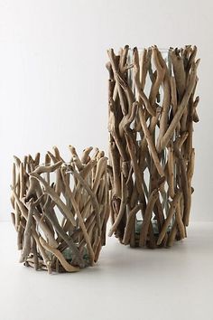 two vases made out of driftwood sitting on a white surface with no one around them