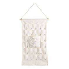 a white wall hanging with an embroidered banner on it's side and the words peace is