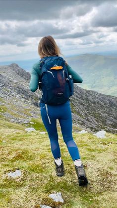 a woman hiking up the side of a mountain with her back turned to the camera