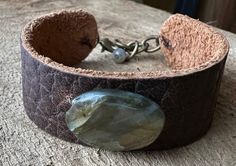 "This unique cuff bracelet is handmade with Labradorite on bark brown textured leather. The labradorite is approx 7/8\" long by 6/8\" wide. I used brass chain and a 6mm labradorite bead at the closure. It's adjustable between 6.75\"-7.75\"  This piece of labradorite has a beautiful golden blue flash." Adjustable Labradorite Cuff Bracelet As Gift, Handmade Adjustable Nature-inspired Cuff Bracelet, Brown Leather Jewelry With Patina, Handmade Distressed Brown Adjustable Bracelet, Rustic Hand Forged Brown Jewelry, Rustic Brown Hand Forged Jewelry, Adjustable Labradorite Bracelet With Unique Style, Artisan Hand Forged Adjustable Cuff Bracelet, Adjustable Patina Cuff Jewelry