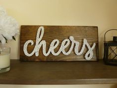 a wooden sign sitting on top of a shelf next to a vase filled with flowers