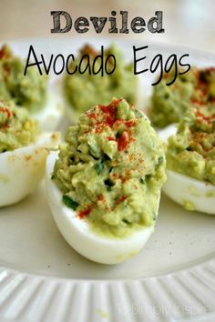 deviled eggs with guacamole and red pepper on top are sitting on a white plate