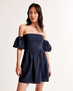 Flattering short-sleeve mini dress in a textured flowy fabric, featuring off-the-shoulder puff sleeves, ruching details along the bodice and waist and center-back smocking for the perfect fit. Recruitment Dresses, Indigo Dress, Flowy Fabric, American Clothing, Dark Indigo, Short Sleeve Mini Dress, Beauty Clothes, New Arrival Dress, Mini Dress With Sleeves