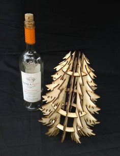 a bottle of wine sitting next to a wooden christmas tree shaped like a pine cone