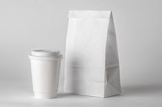 a coffee cup next to a white paper bag