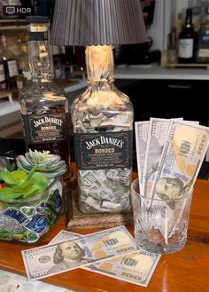 two bottles and money sitting on a counter next to a lamp with a black shade