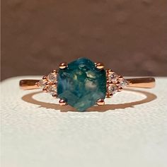 a ring with an oval shaped blue stone surrounded by small white diamonds on a table