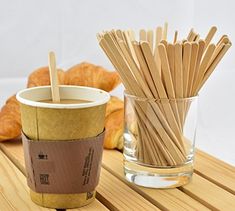 there is a cup with sticks in it and some croissants next to it