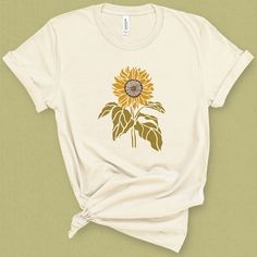 Channel your inner sunflower and reach for the sun in this bright yellow sunflower graphic tee. You'll love this on a warm afternoon, perfect for a BBQ or lazy summer day. This medium weight graphic t-shirt is super soft, comfy, and fits like a well loved favorite tee the first time you put it on. Details 100% superior combed and ring-spun cotton *Heather Blends are 50/50 cotton polly Unisex cut that flatters any figure Printed to order, in the USA, with water based inks Machine Washable, Gentle Sunflower Graphic, Lazy Summer Days, Cut Tees, Yellow Sunflower, Flower Shirt, Tees For Women, Summer Day, Bright Yellow, Graphic Shirts