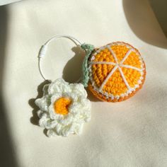 an orange and white crocheted keychain with a flower on it's side