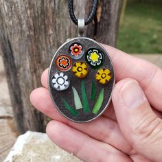 a hand holding a pendant with flowers on it