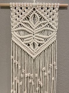 a white wall hanging with macrame beads