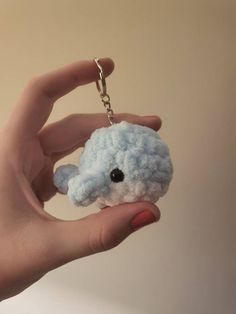 a hand holding a small stuffed animal keychain