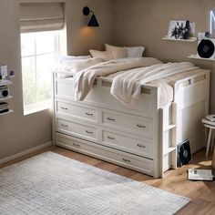 a bedroom with a bed, dressers and rug on the wooden floor next to it