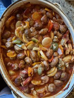 a pan filled with meatballs and vegetables on top of a table