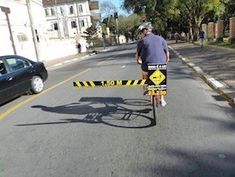 a man riding a bike down a street next to a yellow barricade sign