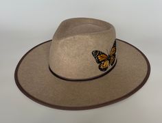 Monarchs migrated through my hometown in Vermont when I was growing up and it was always a magical thing to behold. I wanted to pay tribute through this hat 🧡 It is already embroidered and ready to ship immediately! The hat is hand embroidered and has an teardrop shaped crown with front pinches and a brim width of 4" that is bound with ribbon on the edge. There is a satin interior lining and an adjustable one-size-fits-most sweatband. This hat should fit anyone with a head circumference (where Whimsical Brown Hat With Curved Brim, Handmade High Crown Hats With Adjustable Fit, Unique Handmade High Crown Hat, Adjustable High Crown Handmade Hats, Handmade Adjustable High Crown Hats, Whimsical Fedora Hat As Gift, Whimsical Handmade Short Brim Hat, Custom Curved Brim Hat As Gift, Custom Short Brim Hat As Gift