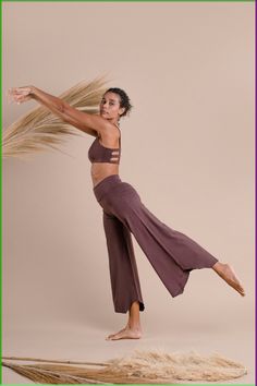 a woman with long hair standing on one leg and holding her arms in the air