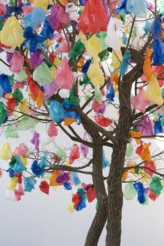 a tree with many colorful pieces of paper hanging from it's trunk and branches