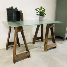 a glass table with wooden legs and a potted plant