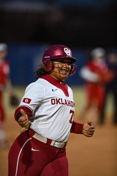 a softball player is running on the field with his hand out to catch the ball