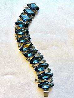 "Beautiful kite shaped blue glass stones on an articulated bracelet band. Smaller light blue crystals on either side, all prong set. This bracelet is in near perfect condition. I have added the safety chain. The closure is a slide in and lock. 7 1/4\" in length by 7/8\" wide." Blue Crystal Bracelets For Formal Occasions, Blue Crystal Bracelet For Formal Occasions, Blue Faceted Crystal Bracelets, Blue Costume Jewelry Bracelets For Formal Occasions, Formal Blue Costume Jewelry Bracelets, Blue Crystal Bracelet With Rhinestones For Party, Blue Sparkling Stones Bracelet For Formal Occasions, Blue Adjustable Jewelry For Evening, Blue Rhinestone Crystal Bracelet For Party