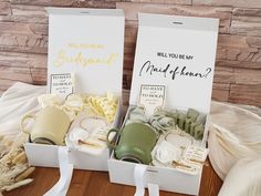 two white boxes filled with different types of wedding gifts on top of a wooden table