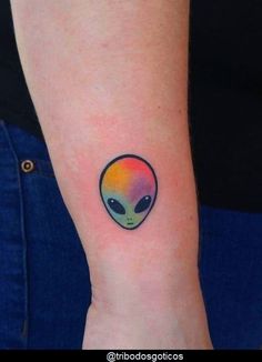 an alien head tattoo on the left inner forearm and wrist is painted in rainbow colors