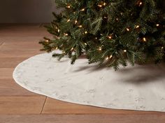 a small christmas tree is on the floor next to a white tablecloth with lights