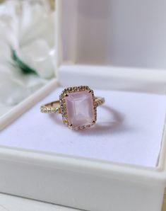 a pink stone ring sitting in a white box