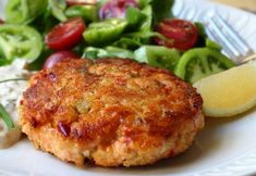 a close up of a plate of food with salad and meat patties on it