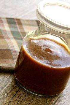 a jar filled with sauce sitting on top of a wooden table