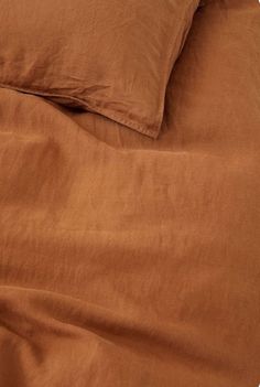 an unmade bed with brown sheets and pillows