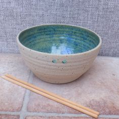 a blue and white bowl with two chopsticks on the ground next to it