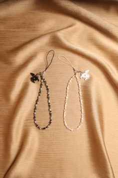 two beaded necklaces are laying on a tan cloth, one is black and the other is white