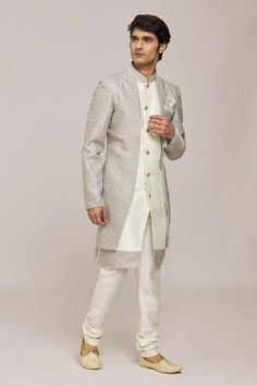 Grey and off white overlay panel  with woven jaal pattern. Comes with churidar.
Components: 2
Pattern: Woven
Type Of Work: Jaal
Neckline: Mandarin Collar
Sleeve Type: Full
Fabric: Sherwani: Alfi Jacquard, Silk Dupion,Churidar: Silk Dupion
Color: Grey,Off White
Other Details: 
Asymmetric hem
Embellished buttons
Closure:
Sherwani: Front button
Churidar: Drawstring
Note: Pocket square worn by the model is not for sale
Occasion: Sangeet,Mehendi and Puja - Aza Fashions Semi-stitched Chanderi Sherwani With Cutdana, Formal Off White Set With Traditional Drape, Formal Off White Sets With Traditional Drape, Off White Designer Wear Sets For Transitional Season, Off White Designer Sets For Transitional Season, Festive Off White Nehru Jacket With Naqshi, Formal White Nehru Jacket With Straight Kurta Shape, Festive Off-white Nehru Jacket With Naqshi, White Bandhgala With Zari Work In Raw Silk